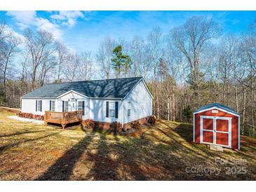 Charming one-story home with a wooden deck and a red storage shed nestled on a sprawling lot with mature trees at 4845 Midway Sand Rd, Hickory, NC 28601