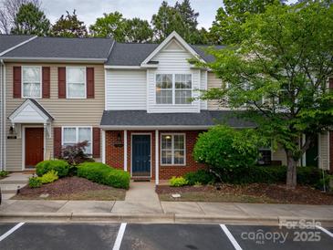 Charming townhouse featuring a brick facade, blue door, manicured landscaping, and red shutters at 118 Barnhardt Loop, Mooresville, NC 28117