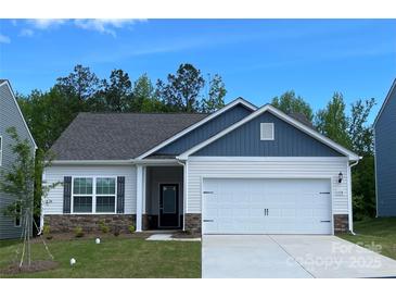 Charming single-story home with a two-car garage, stone accents, and vinyl siding against a clear blue sky at 1528 Doran Ter, Richburg, SC 29729