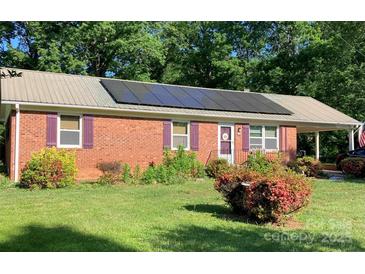 Charming brick home featuring solar panels, colorful shutters, a metal roof, and a well-maintained front yard at 1750 Sells Rd, Salisbury, NC 28144