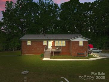 Charming brick home featuring a metal roof, inviting front porch and well-manicured lawn, perfect for peaceful living at 1792 Hoffman Rd, Gastonia, NC 28054