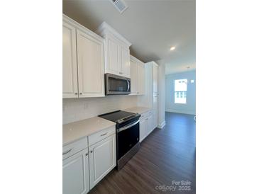 Modern kitchen features white cabinets, stainless steel appliances, quartz countertops, and subway tile backsplash at 2013 Clarksdale Dr # 38, Charlotte, NC 28206