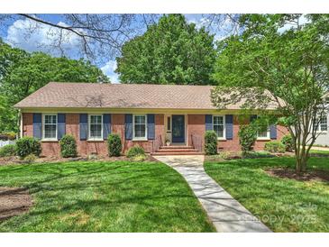 Charming brick home with blue shutters, lush lawn, and inviting walkway leading to the front door at 3901 Kitley Pl, Charlotte, NC 28210