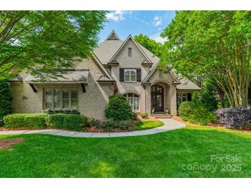 Charming brick home featuring a manicured lawn, mature trees, and elegant landscaping at 7138 Wessynton Dr, Charlotte, NC 28226