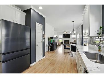 Modern kitchen featuring stainless steel appliances and wood flooring, seamlessly flowing into an open living space at 8833 Cavonnier Ln, Charlotte, NC 28216