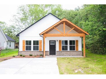 Charming new construction home featuring a farmhouse style with wood accents and shutters with a well manicured lawn and concrete driveway at Lot 1 New Pineola Rd, Charlotte, NC 28208