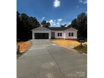 Charming white home with an attached garage and a long driveway nestled amongst mature trees at 3137 Riber Ln, Claremont, NC 28610