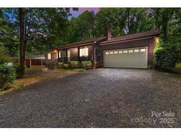 Charming home featuring a two-car garage and inviting front porch, surrounded by lush trees and a spacious driveway at 503 Overbrook Dr, Albemarle, NC 28001