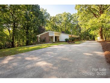 Ranch style home with brick accents, a long driveway, and mature trees surrounding the property at 981 Sherwood Cir, Lancaster, SC 29720