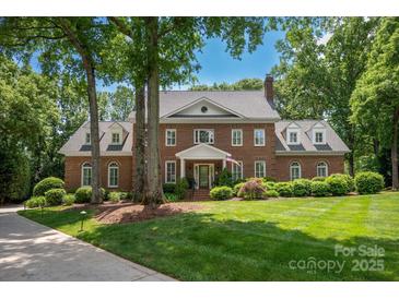 Stately brick home features mature trees, manicured lawn, and classic architectural details at 12048 Royal Portrush Dr, Charlotte, NC 28277