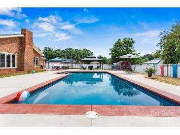 Backyard features a sparkling in-ground pool with a gazebo and patio furniture for relaxing and entertaining at 312 Rumple St, Troutman, NC 28166