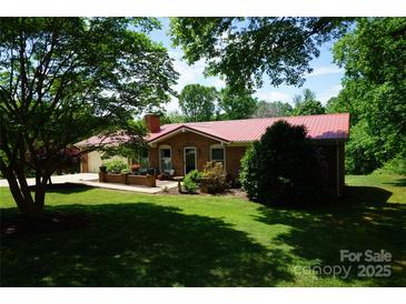 Charming brick home featuring a well-manicured lawn, red roof, and lush greenery at , Hickory, NC 28602