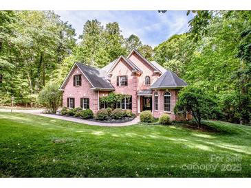 Charming brick home with a well-manicured lawn and lush, mature trees at 112 Eagle Chase Ln, Troutman, NC 28166
