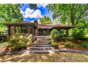Charming log cabin home featuring stone steps, lush landscaping, and a serene, wooded setting at 6510 Sharon Hills Rd, Charlotte, NC 28210