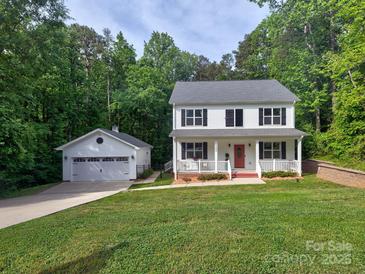 Charming two-story home with a red door, white trim, detached garage, and a well-manicured lawn at 1904 Lark Ln, Stanley, NC 28164