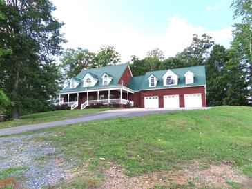 Inviting brick home with a green roof, white trim, and a spacious three-car garage on a lush, green lawn at 2530 Sharon Rd, York, SC