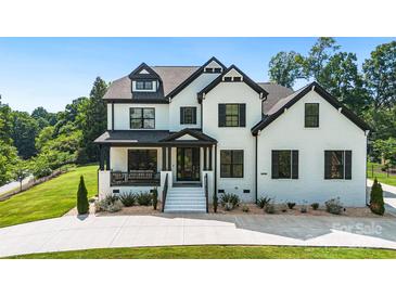 Elegant two-story home with a white brick exterior, black trim, well-manicured lawn and beautiful landscaping at 2854 Harlinsdale Dr, Rock Hill, SC 29732