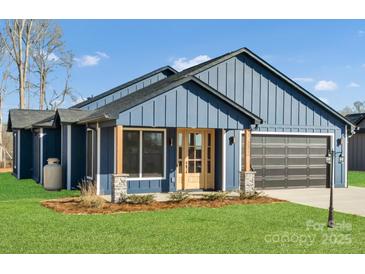 Charming home with a blue exterior, complemented by a well-manicured lawn and inviting front porch at 32507 Buchanan Ln, Albemarle, NC 28001