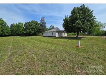 Quaint single-story home featuring a metal roof and a sprawling, well-maintained lawn with mature trees at 5501 Barrier Rd, Concord, NC 28025