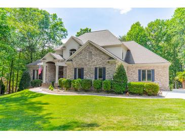 Charming, two-story brick home with blue shutters, landscaped yard, and an American flag at 123 Archbell Point Ln, Mooresville, NC 28117