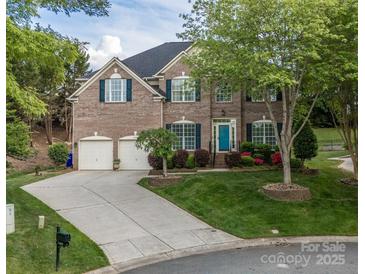 Brick home with two-car garage, lush landscaping, and a blue front door adds curb appeal at 15406 Pepperwood Ct, Huntersville, NC 28078