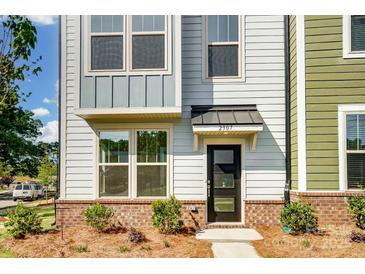 Charming townhome exterior featuring light blue siding, brick accents, and a stylish black front door at 2907 W Trade St, Charlotte, NC 28208