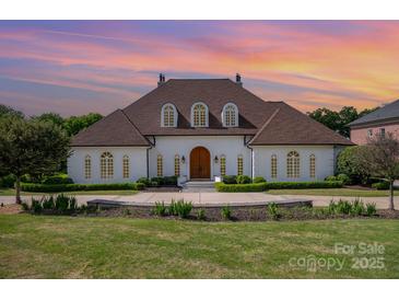 Elegant home with a manicured front lawn and refined landscaping, highlighted by an arched front door at 5400 Challisford Ln, Charlotte, NC 28226