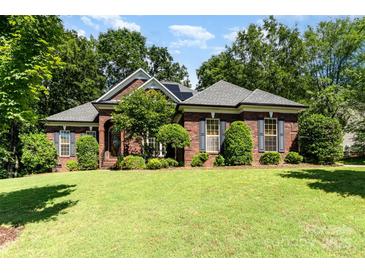 Charming brick home with well-manicured lawn, mature trees, and inviting curb appeal at 7587 Long Valley Dr, Harrisburg, NC 28075