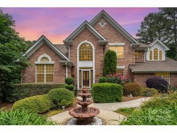 Inviting brick home featuring a meticulously landscaped front yard with lush bushes, blooming flowers, and a charming water fountain at 118 Sunrise Cir, Mooresville, NC 28117