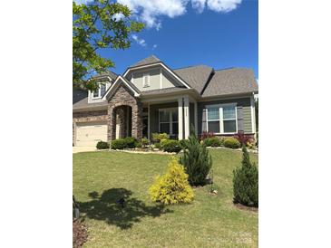 Beautiful home featuring a stone archway entry and a well-maintained lawn with colorful landscaping at 10039 St Kitts Landing Ln, Charlotte, NC 28278
