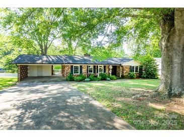 Charming one-story brick home with black shutters and a covered carport under mature trees at 1211 Starlight Dr, Shelby, NC 28152