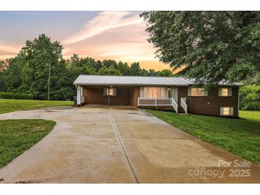 Charming brick home with a metal roof, carport, and a spacious driveway at sunset at 133 Jo Monni Loop, Statesville, NC 28625