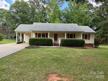 Charming single-story home featuring red shutters, a carport, and lush green landscaping at 1833 Bardell St, Lancaster, SC 29720