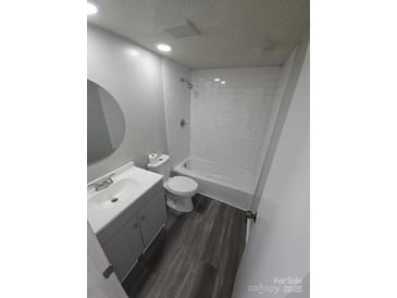 Well-lit bathroom with white subway tile surround and gray wood-look flooring at 7129 Stonington Ln, Charlotte, NC 28227