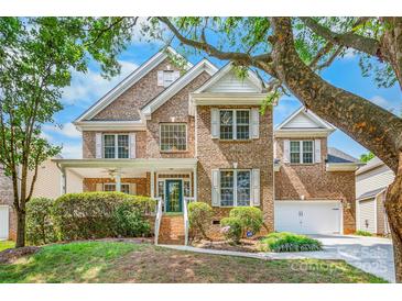 Charming brick home with lush landscaping, white shutters, and a welcoming front porch at 14426 Harvington Dr, Huntersville, NC 28078