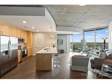 Open kitchen with stainless appliances, island with seating, and living area views at 210 N Church St # 2613, Charlotte, NC 28202