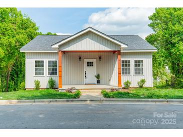 Charming home with light siding, covered front porch, and well-manicured lawn at 322 S Hill St, Gastonia, NC 28052