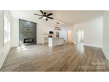 Bright, open-concept living area featuring a modern fireplace, ceiling fan, and a stylish kitchen island at 322 S Hill St, Gastonia, NC 28052