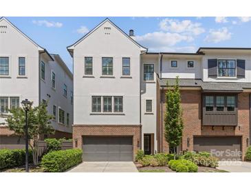 Modern townhome exterior featuring a gray garage door, a combination of stucco and brick, and a well-maintained lawn at 4030 City Homes Pl, Charlotte, NC 28209