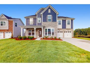 Charming two-story home boasts stone accents, blue siding, well-manicured lawn, and attached two car garage at 8286 Ashvale Nw St, Concord, NC 28027