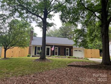Charming single-story home featuring a brick facade, attached garage, and a neatly maintained front yard surrounded by mature trees at 9207 Branson Ct, Charlotte, NC 28210