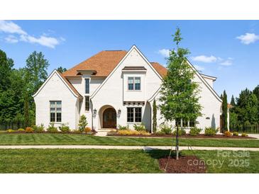 Stunning white brick home with a manicured lawn, arched entry, and a warm, inviting presence at 10201 Laurier Ln, Huntersville, NC 28078