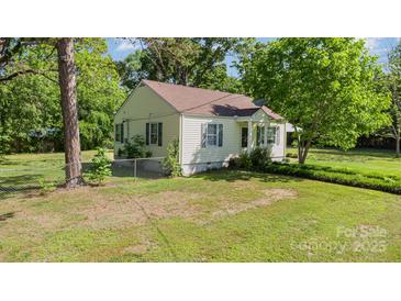 Charming single-story home with yellow siding, brown roof, and lush surrounding trees, nestled in a serene neighborhood at 1302 N Ellis St, Salisbury, NC 28144