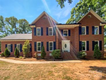 Charming two-story brick home with manicured landscaping and classic blue shutters on a sunny day at 1507 Chadmore Nw Ln, Concord, NC 28027