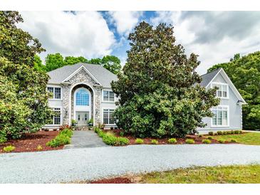 Stately home with stone facade, arched entryway, mature landscaping, and gravel driveway at 1720 Mills Harris Rd, Wingate, NC 28174