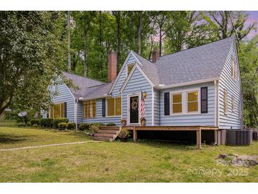 Charming light-blue home featuring a covered porch, manicured lawn, and mature trees providing a serene backdrop at 200 Cleveland Ave, Shelby, NC 28150