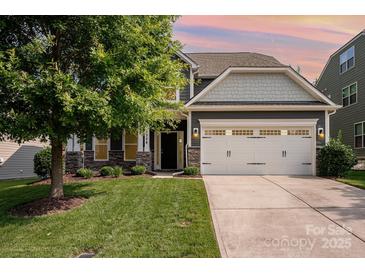 Charming two-story home featuring a well-manicured lawn, attached garage, and beautiful stone accents at 4324 Falls Lake Sw Dr, Concord, NC 28025