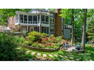 Expansive brick home featuring a spacious screened porch and beautifully landscaped backyard with lush gardens and a seating area at 4647 16Th Street Ne Pl, Hickory, NC 28601