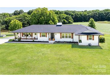 Charming white brick home with a black roof and shutters set on a large lawn at 5710 Lander Benton Rd, Unionville, NC 28110