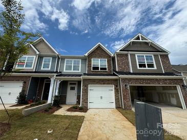 New townhomes with brick and siding exteriors, showcasing modern design and attached garages under a cloudy sky at 6256 Culbert St # 187, Harrisburg, NC 28075